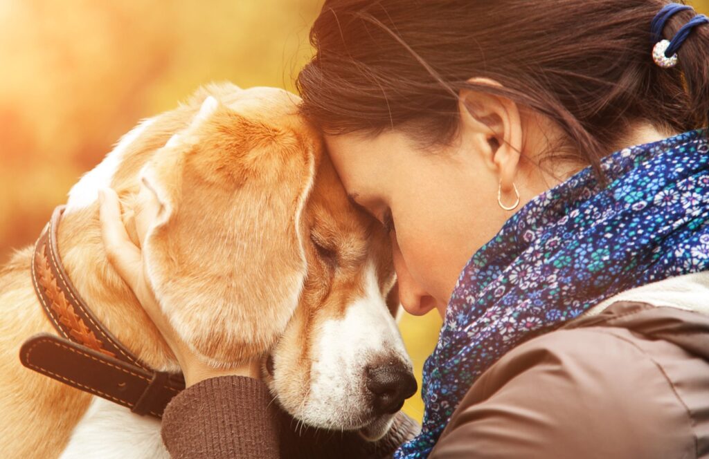 O femeie își ține capul lipit de capul unui câine
