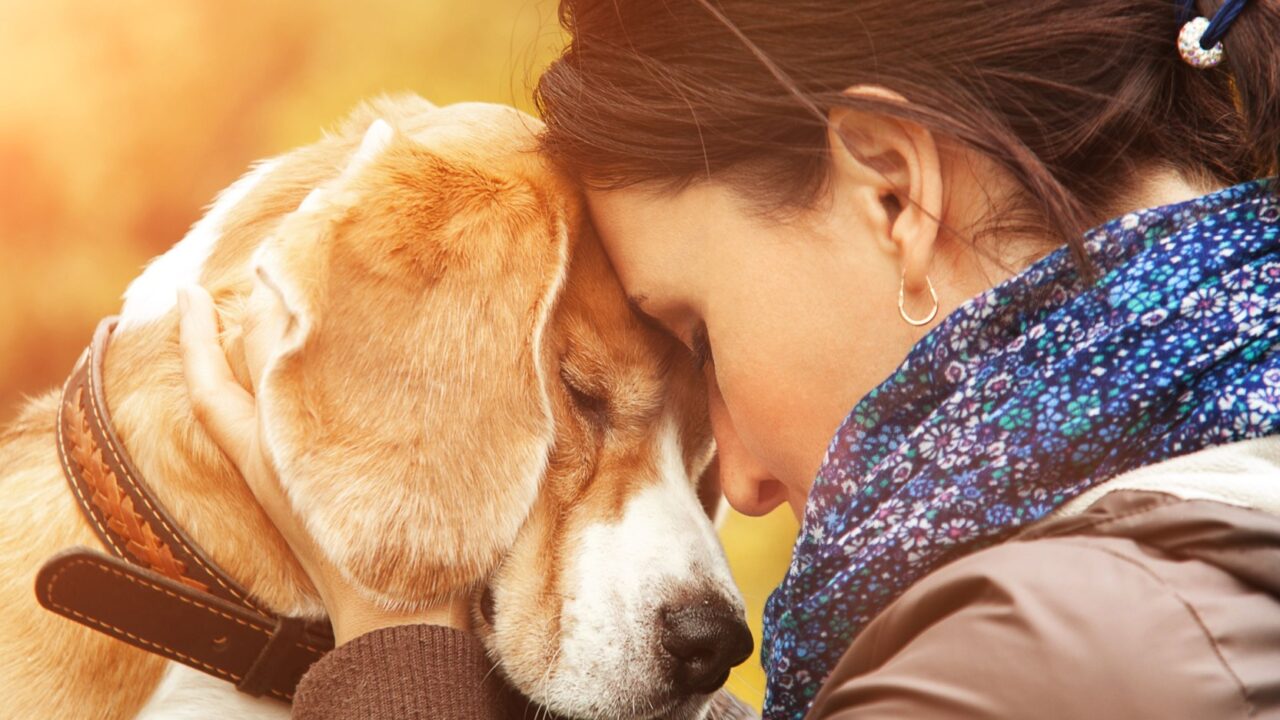 O femeie își ține capul lipit de capul unui câine