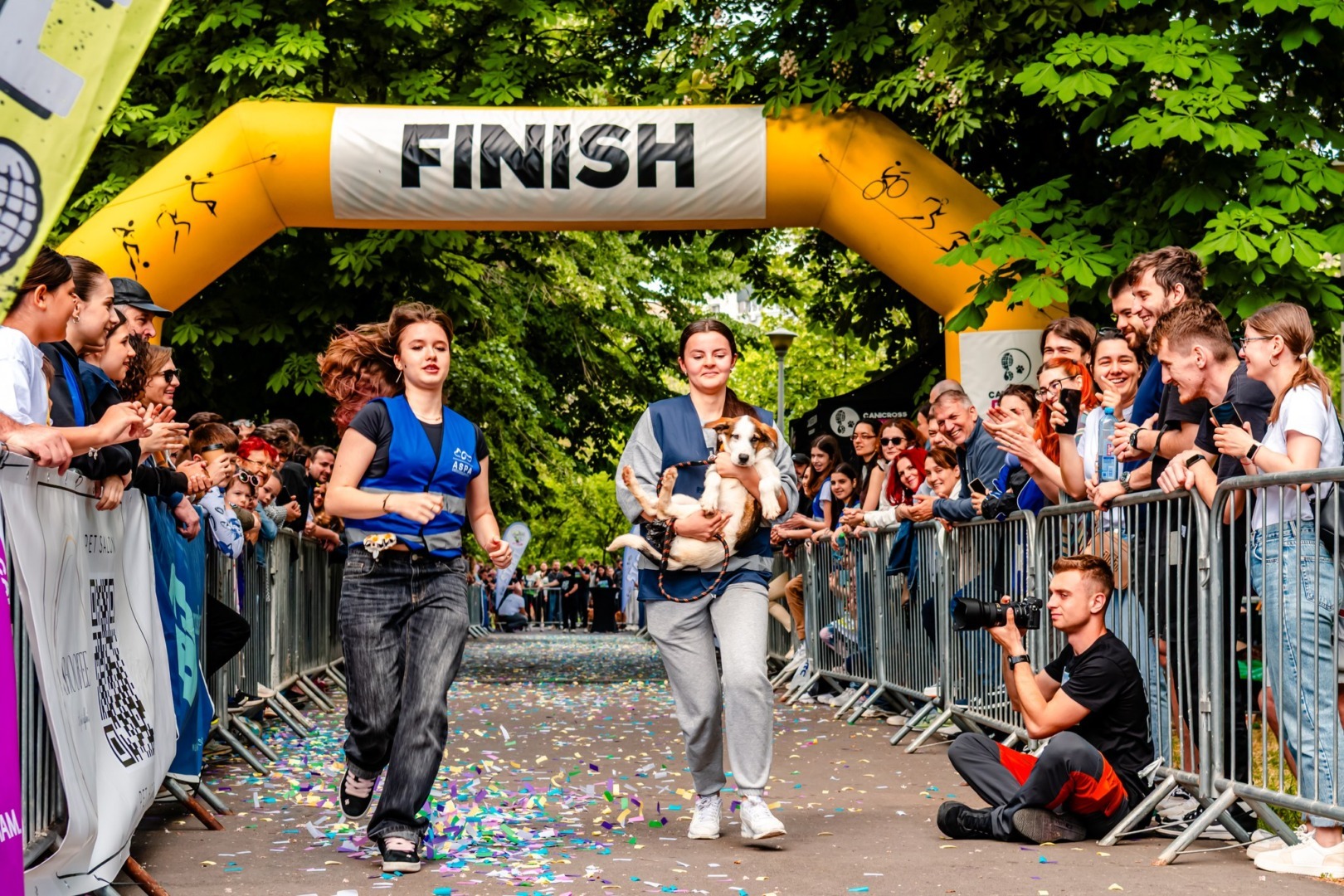 Două tinere și un cățel trec linia de sosire la Canicross Fun Run