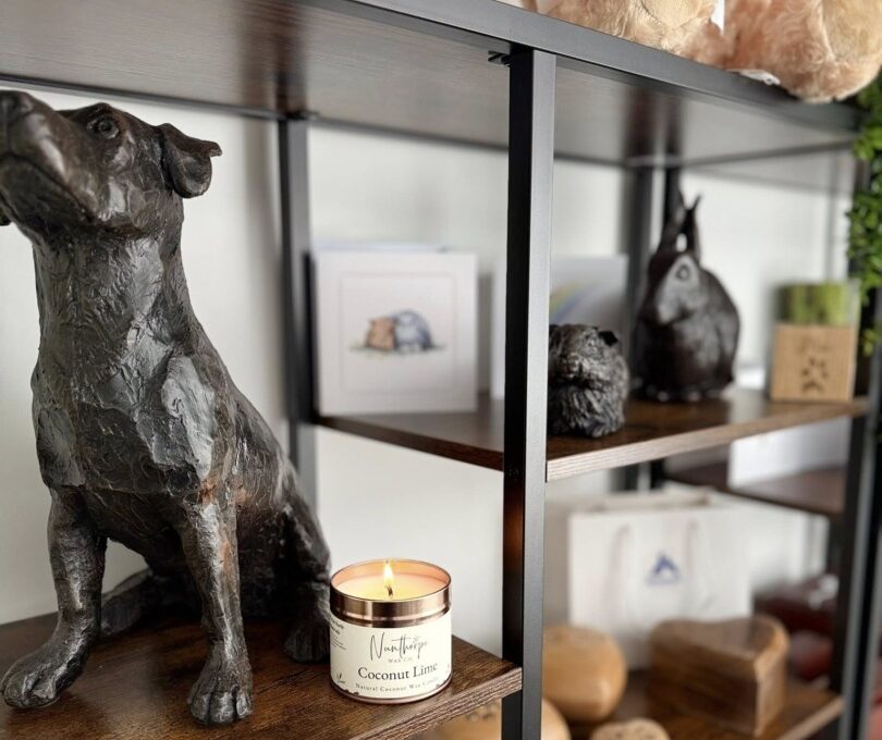 Statueta unui câine, pe un raft, alături de o lumânare.