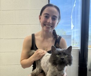 O femeie își ține pisica în brațe.