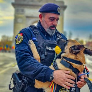 Un jandarm ține în brațe un câine utilitar