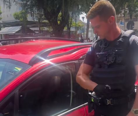 Un polițist spaniol sparge geamul unei mașini.