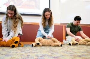 Studenți exersând manevre de resuscitare pe jucării de pluș.
