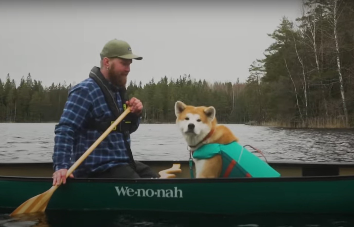 Câine cu vestă de înot, alături de stăpânul lui, în canoe