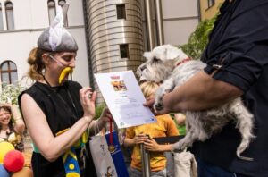 Câine ținut în brațe lângă o persoană deghizată în Asterix