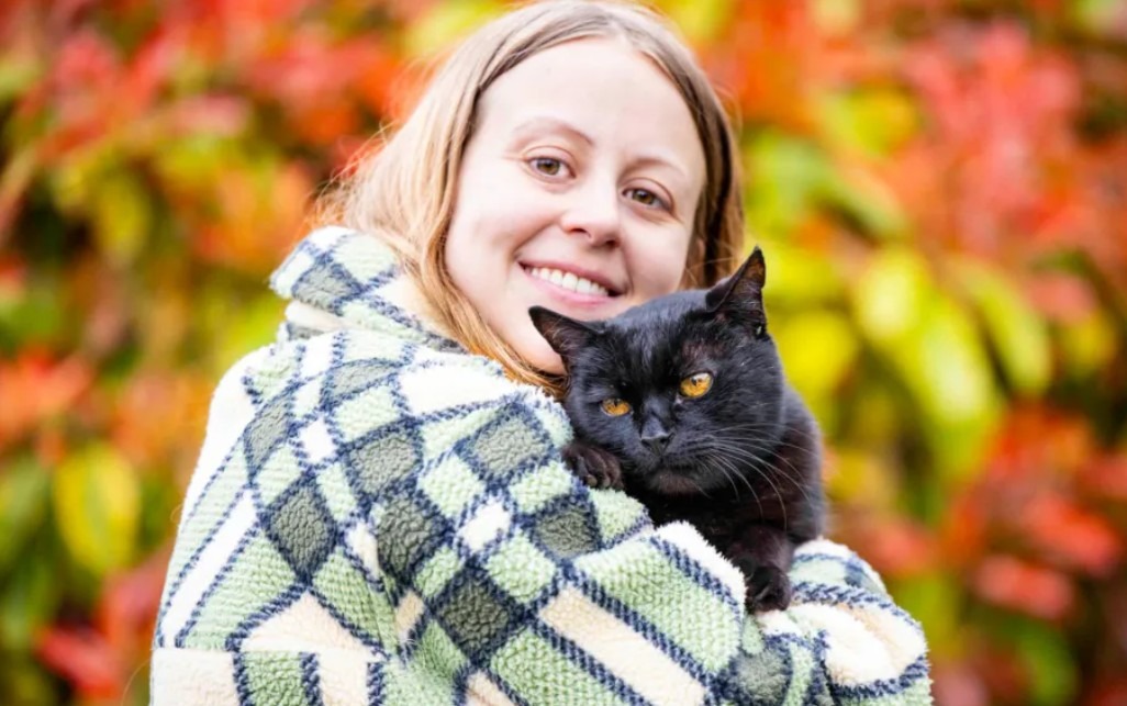 Motan negru ținut în brațe de stăpâna lui