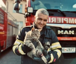 Pisică ținută în brațe de un pompier
