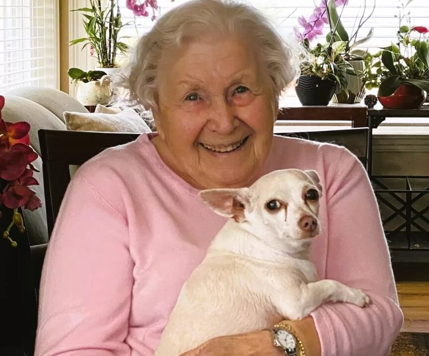 O bătrână ține în brațe un cățel