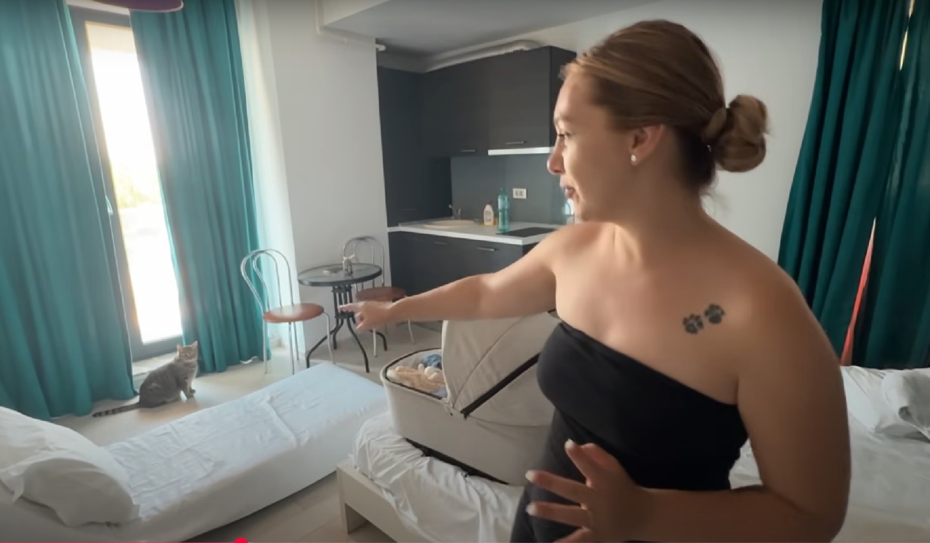 O tânără în camera unui apartament și o pisică la geam.