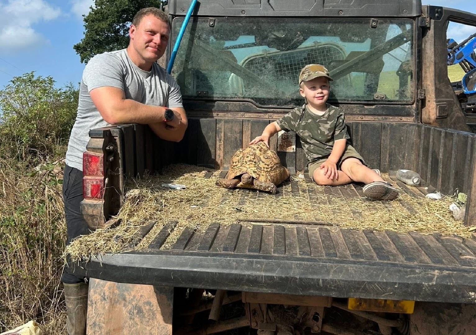 Un copil și o țestoasă în portbagajul unei mașini, iar alături este tatăl copilului