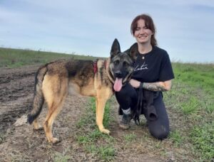 O tânără alături de câinele ei, pe câmp