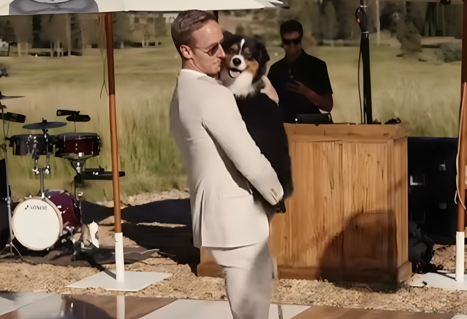 Un bărbat îmbrăcat în alb dansează cu câinele în brațe