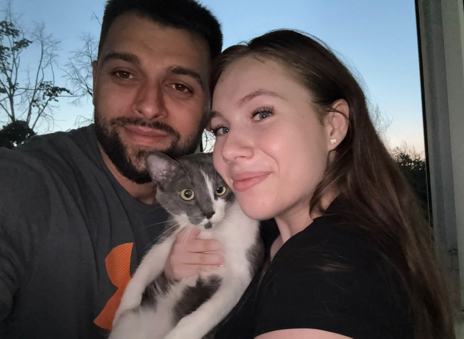 Doi tineri țin în brațe un pui de pisică