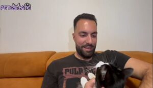 Un tânăr își ține motanul în brațe