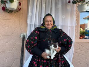Femeie din Țara Oașului îmbrăcată în port popular, cu o pisică în brațe