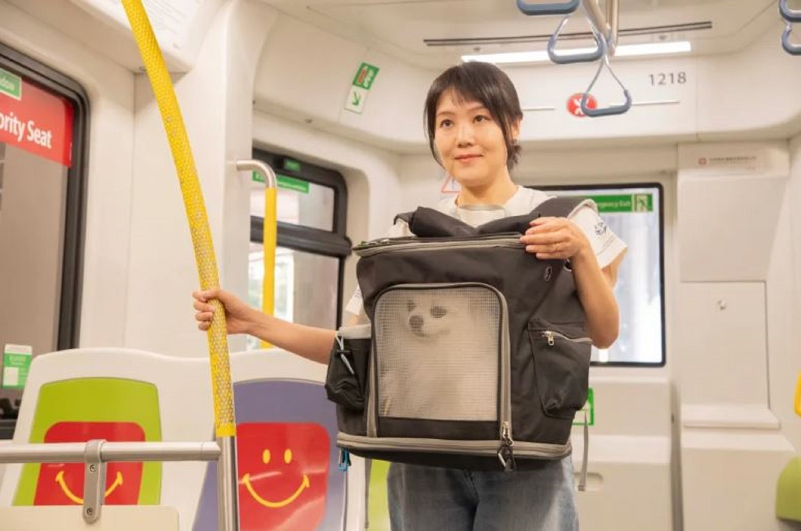 O tânără ține în brațe un rucsac în care se află un câine alb, într-un metrou din Hong Kong