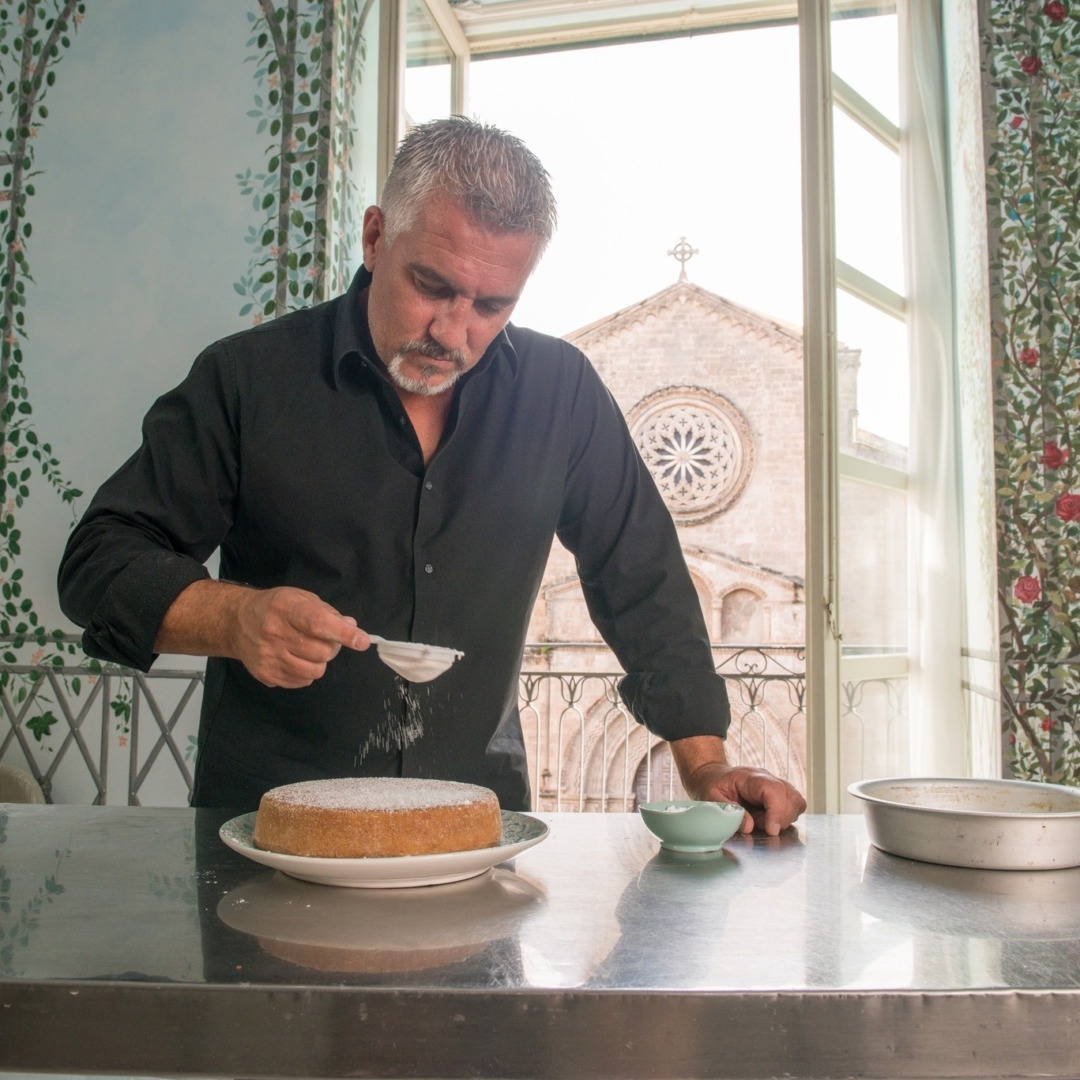 Bucătarul Paul Hollywood presară zahăr pudră pe o prăjitură