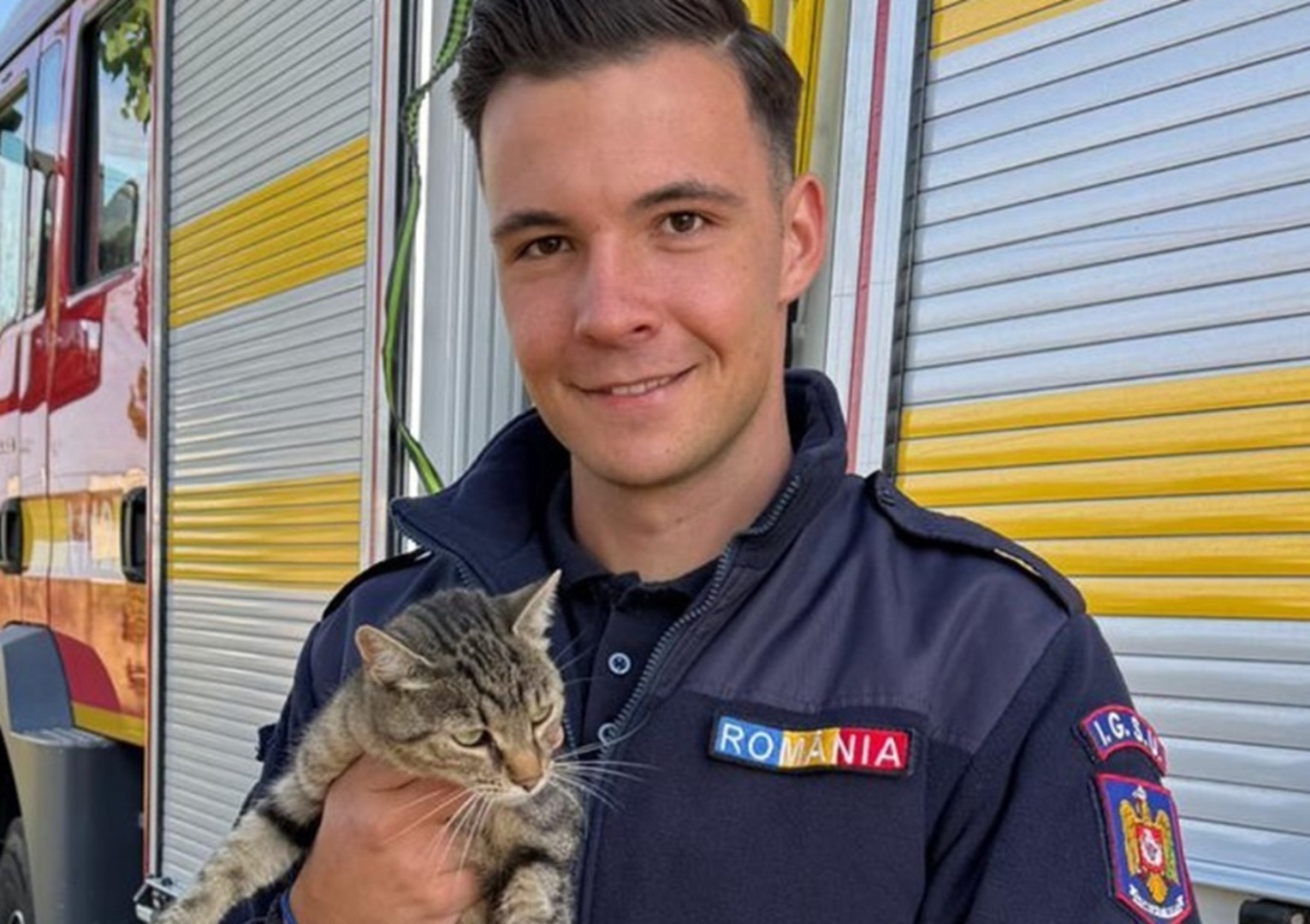 Un pompier ține în brațe pisica pe care a salvat-o dintr-o fântână