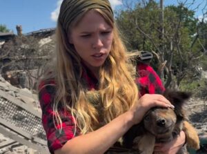 O tânără ține un câine în brațe, în urma unui bombardament în ucraina