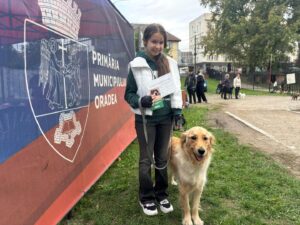 O elevă alături de câinele ei, lângă un panou informativ