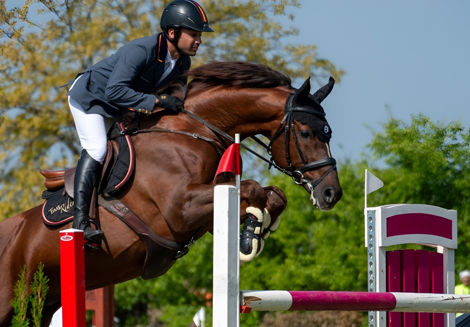 Un cal care poartă în spate un călăreț sare peste un obstacol la un concurs de echitație