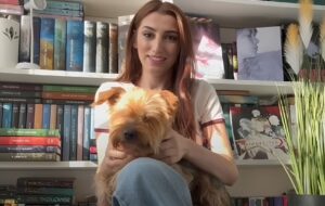Isabela Oprea, șefa Protecției Animalelor Sector 1, își ține câinele în brațe în fața unei biblioteci