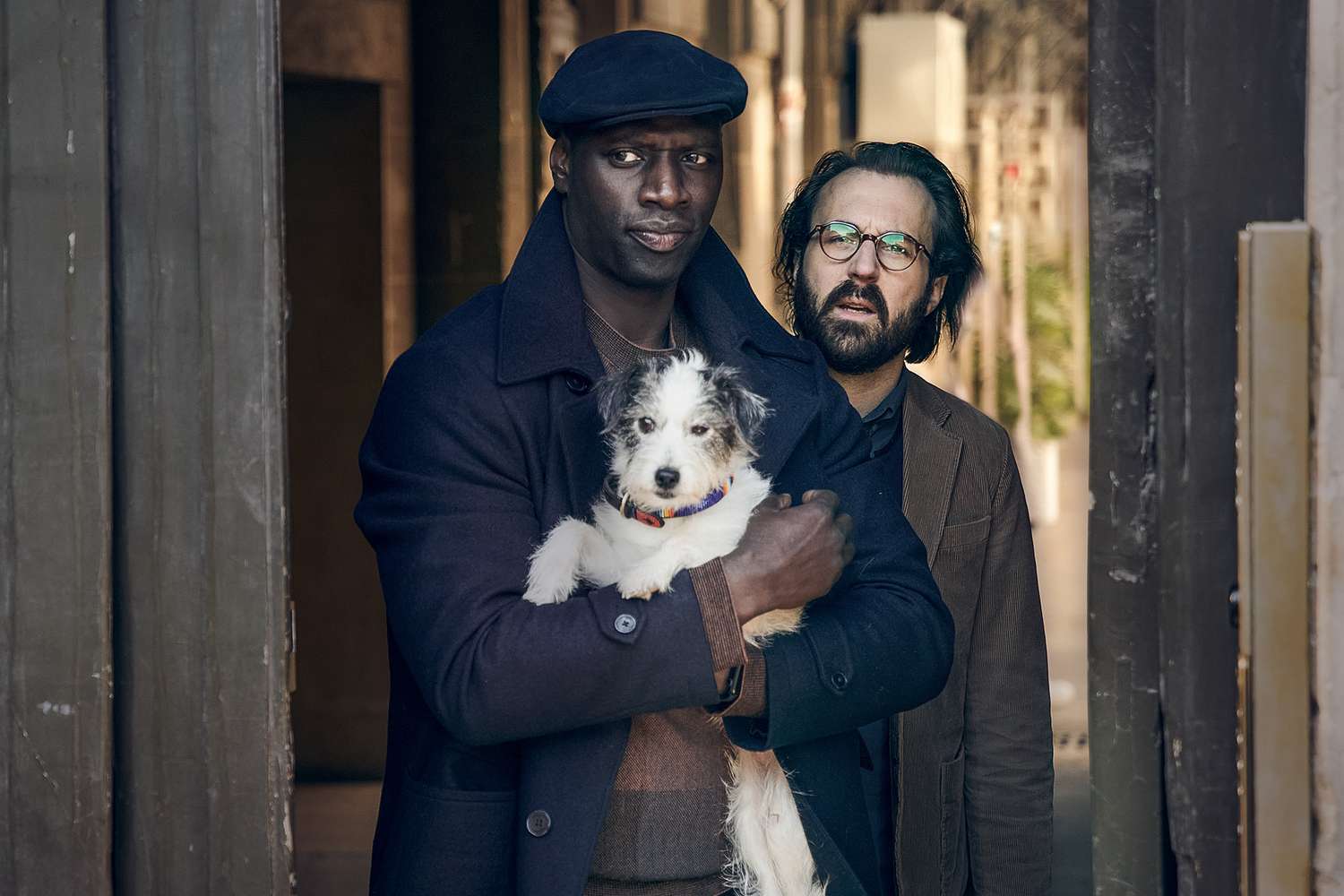 caine ținut în brațe de stăpân, în spatele lor este un bărbat