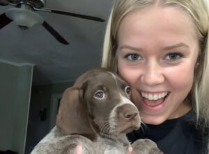 O tânără își ține cățelul în brațe în timp ce râde