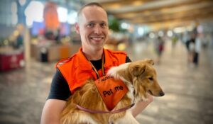 Angajatul unui aeroport ține în brațe un câine