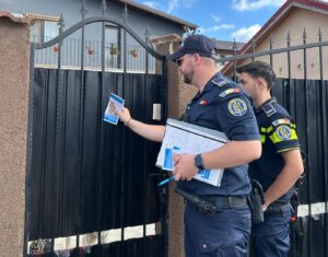 Doi polițiști introduc pliante în cutia poștală