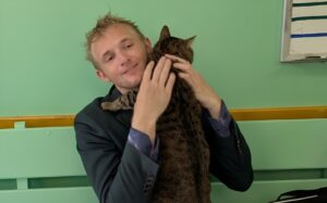 Un bărbat își ține pisica în brațe