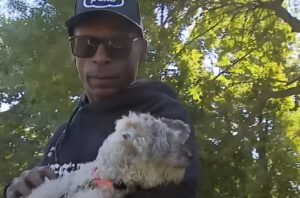 un barbat isi tine cainele in brate intr-un parc