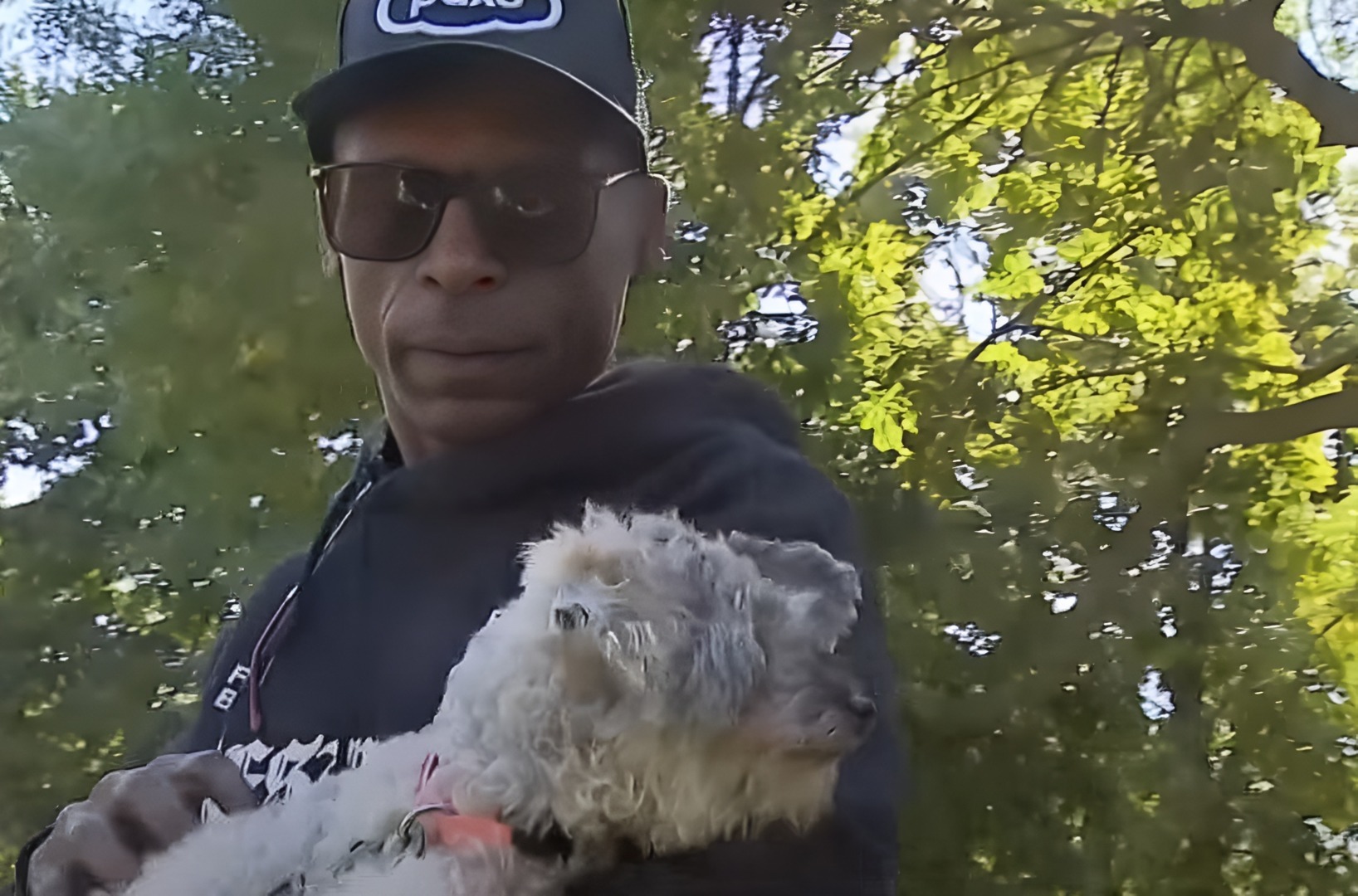 un barbat isi tine cainele in brate intr-un parc