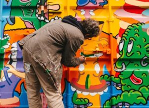 Un artist stradal realizează un graffiti