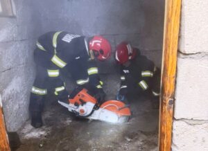 Pompieri încercând să salveze un câine blocat într-o fosă