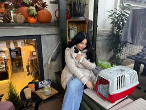 O tânără ține în brațe o pisică adoptată, într-o cafenea