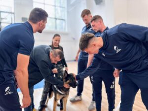 Rugbiști români într-o sală de sport, alături de câinele polițist Aron