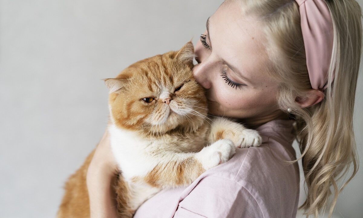 O tânără își ține pisica în brațe