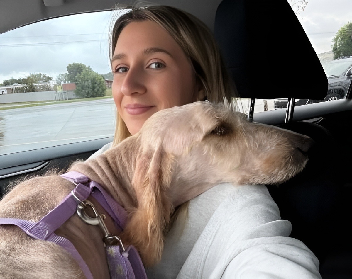 O tânără ține un câine în brațe, în mașină