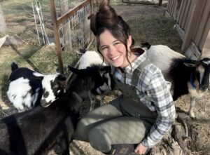 O tânără stă printre animalele de la fermă