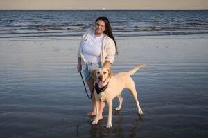 Un câine și stăpâna lui se plimbă pe o plajă