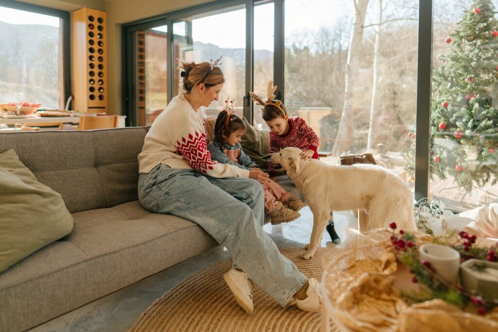 O mamă și doi copii se joacă cu câinele, de Crăciun