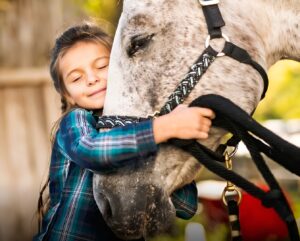 Un copil îmbrățișează un cal