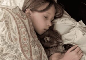 O fetiță doarme alături de o pisică