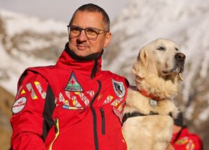 Câinele utilitar Yukanna alături de un salvator montan