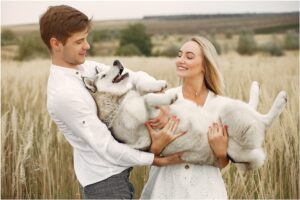 Cuplu ținând în brațe un câine Husky