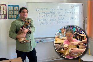 Profesor care tine în brațe un câine, în fața unei table pe care scrie un mesaj pentru copii