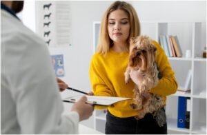 femeie cu un caine in brate care semneaza un formular