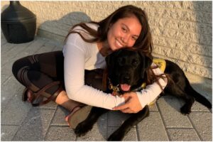 O tânără care îmbrățișează un câine negru